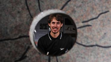PhD student Luke Frash is seen through a cross-section of a fractured granite specimen.
