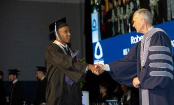 President Johnson shakes hands with graduate
