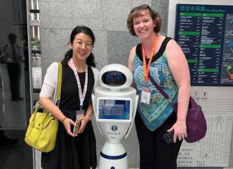 CUMT librarian Jie Bao shows Brianna Buljung a robot they use in their library.