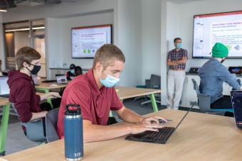 Student wearing a mask working on a computer in classroom