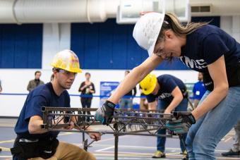 Male and female Mines student assemble steel bridge