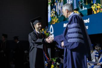 Male graduate shakes hand of Mines President Paul C Johnson