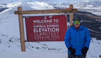 Emmette standing next to elevation sign on Breckenridge mountain peak