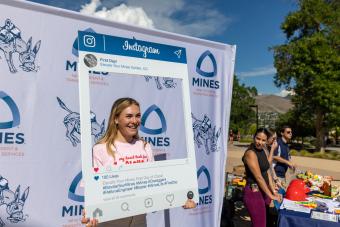 Mines student poses with Instagram backdrop