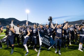 Mines football players celebrate with championship game banner