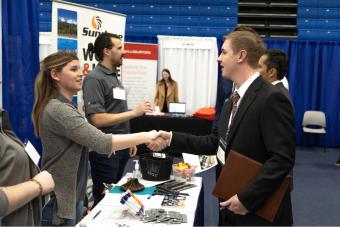 Male student shakes hand with female recruiter