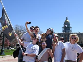 Students pose in front of state Capitol with MAC flag
