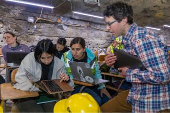 Two students with professor in underground classroom