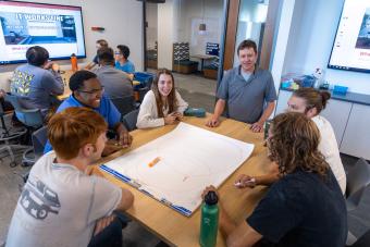 Table of students talks to professor during Design I