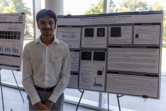 Student stands in front of his research poster on nanobody therapeutics.