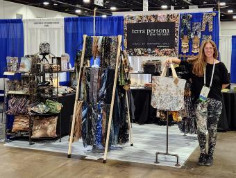 Teresa Johnson poses with Terra Persona booth at trade show