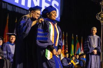 PhD graduate during hooding ceremony at 2022 midyear commencement