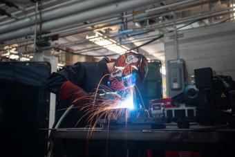 Person in welding shield welding with sparks flying