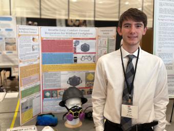 Male high school student stands in front of research poster board