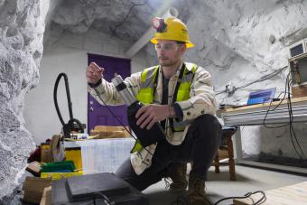 PhD student in safety gear in an underground mine chamber working on a scintillator