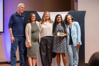 Five people stand on stage with award
