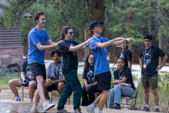 three students with hands on shoulders performing skit