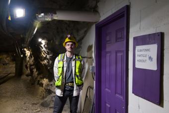 PhD student in safety gear in an underground mine chamber