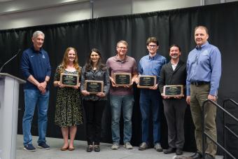 five faculty members standing on stage holding awards