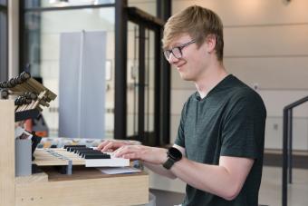 male student with hands on keyboard of new instrument