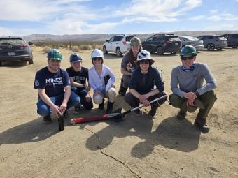 Mines Rocket Club members pose with rocket in desert