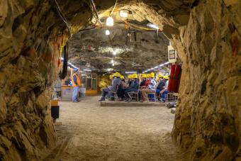 Students wearing yellow hard hats sitting at desks in the classroom in Edgar Mine. A professor in a blue hard hat faces them at the front of the room.