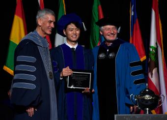 Xue Wang holding Rath plaque with President Johnson and VP Copan