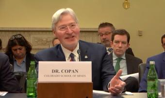 Walt Copan sits at witness stand with people taking notes behind him