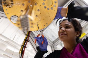 female researcher in blue gloves works on gold dilution refrigerator