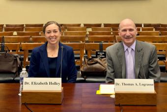 Elizabeth Holley sits at a table behind white name tent with fellow scientist