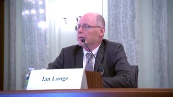 Ian Lange sits at table behind white name tent