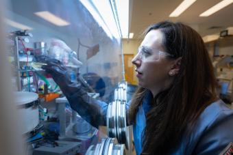 female researcher in safety glasses works in fume hood