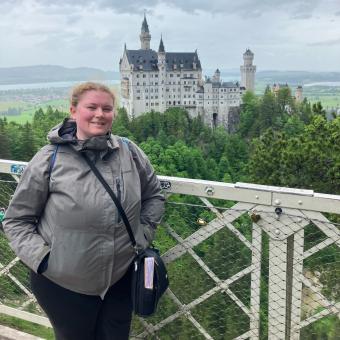 Female in gray coat posing with castle in background