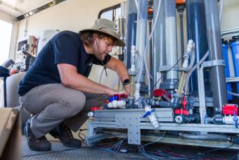 male researcher in hat works on pfas treatment system inside a trailer