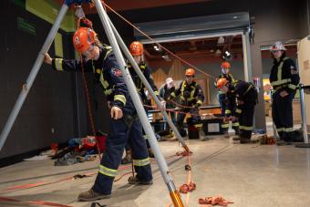 students in orange helmets and safety suits compete at mine rescue competition
