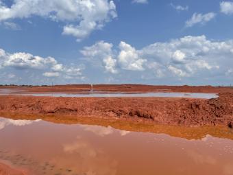red mud tailings with clouds reflected in water