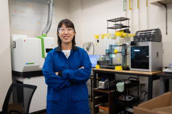 Jihye Kim stands in the lab in a blue lab coat
