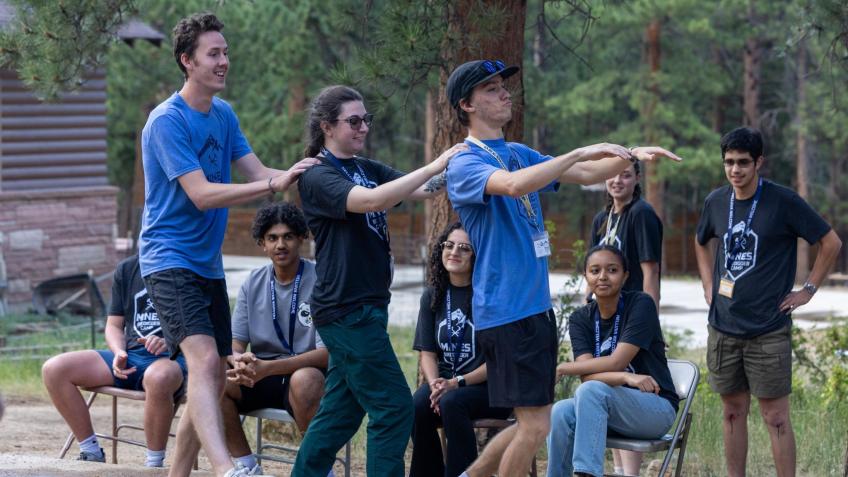 three students with hands on shoulders performing skit