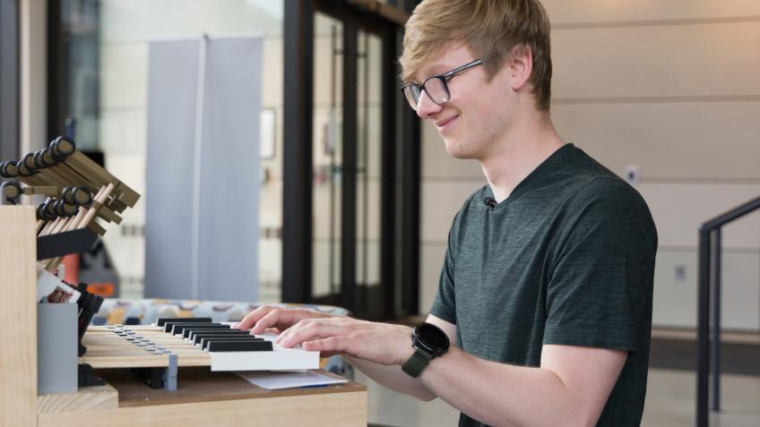 male student with hands on keyboard of new instrument