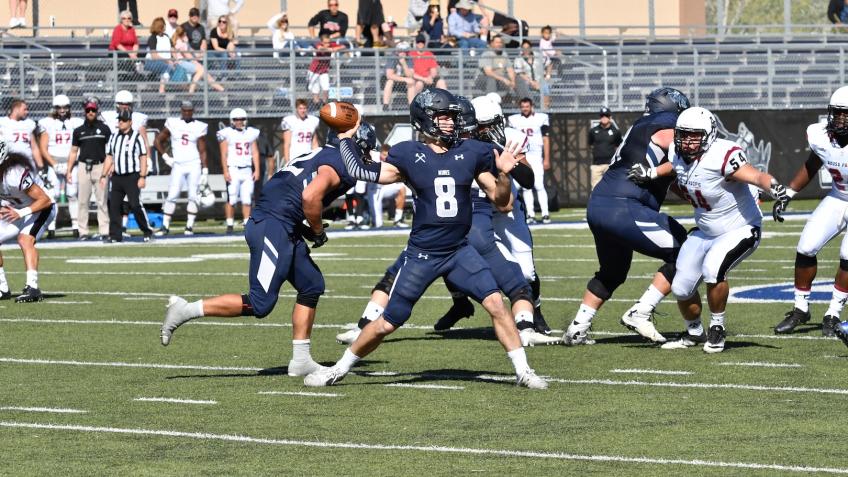Justin Dvorak gets ready to throw a football surrounded by other football players during a Mines football game
