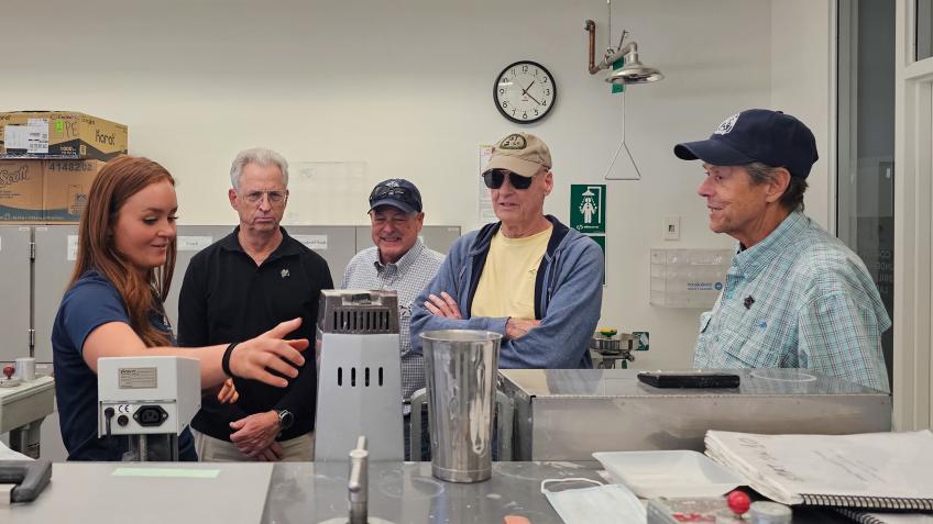 four male alumni get lab tour from female student