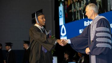 President Johnson shakes hands with graduate