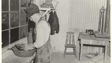 A man wearing overalls performs a pan test in a rough laboratory.