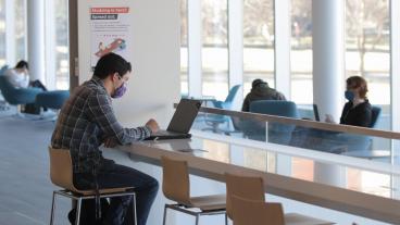 Student works on computer in CoorsTek atrium