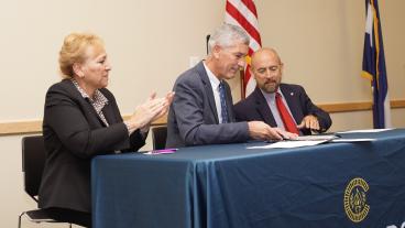 Paul Johnson, center, signs agreement with Joe Garcia and Angie Paccione