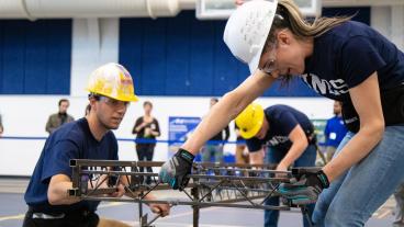 Male and female Mines student assemble steel bridge