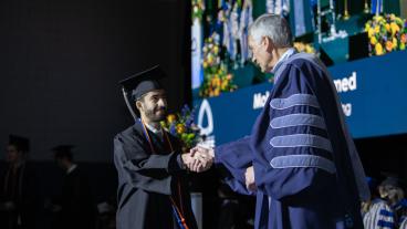 Male graduate shakes hand of Mines President Paul C Johnson