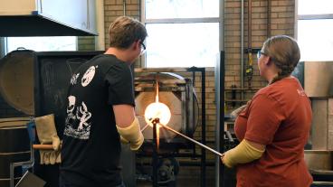 Male and female student making glass