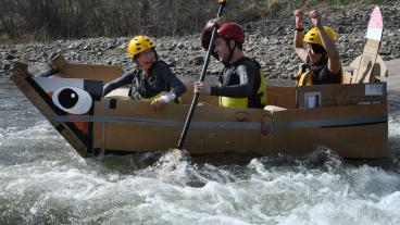 Three students in cardboard boat