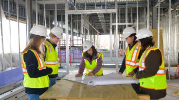Mines students look at blueprints inside Beck Venture Center construction site